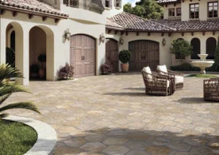 Mediterranean courtyard with arched doorways, wooden garage doors, tiled roof, and a seating area by a stone fountain.