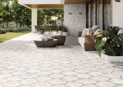 Modern outdoor patio with stone-patterned flooring, wicker seating, and potted plants under a shaded seating area