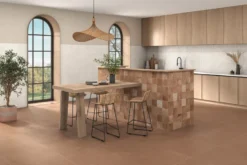Modern kitchen with a tiled island, wooden cabinets, and a rustic dining table with woven stools under a hanging wicker light.