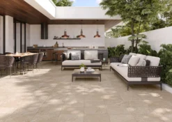 Modern outdoor lounge and kitchen area with copper pendant lights, dining table, and sectional seating among greenery.